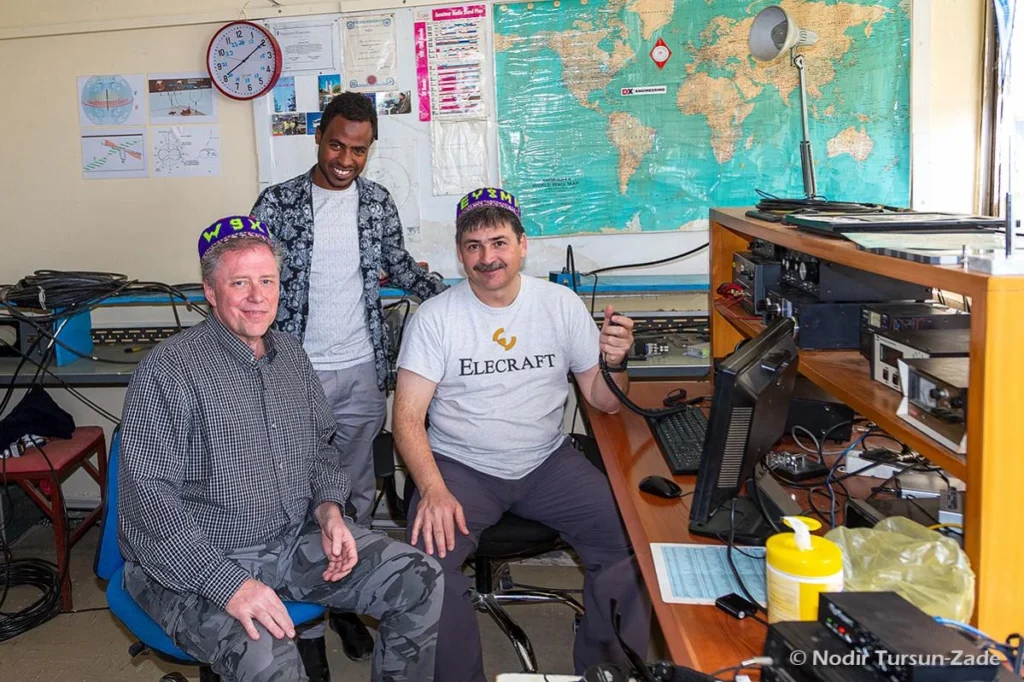 Equipe de radioamadores em estação HF/FT8 na Etiópia, com equipamentos de comunicação.