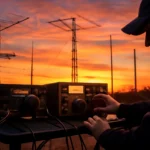 Capa do CQ WW WPX Contest mostrando estação de rádio ao amanhecer com antenas e operadores ajustando equipamentos