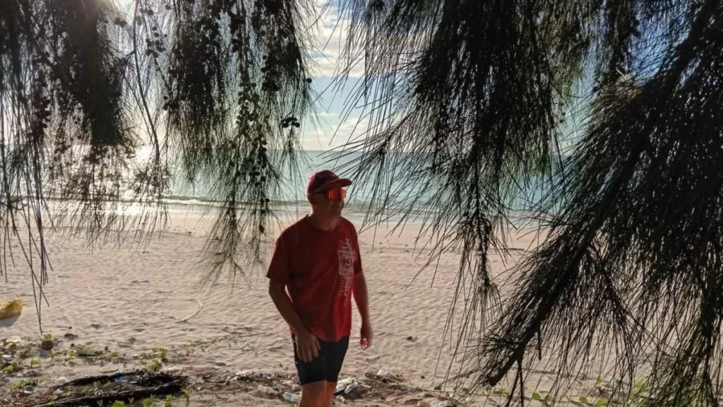 Homem caminhando na praia sob árvores em Ilhas Comores.