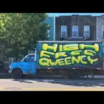 Caminhão azul com grafite 'HIGH FREE QUEENCY' em destaque